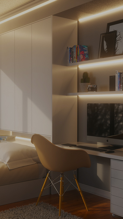This is an image of Nanoleaf Essentials Lightstrips in a bedroom office above the desk and monitor. The smart lightstrips are mounted below the floating shelves and the back light is perfect for finding inspiration or boosting productivity while you work.
