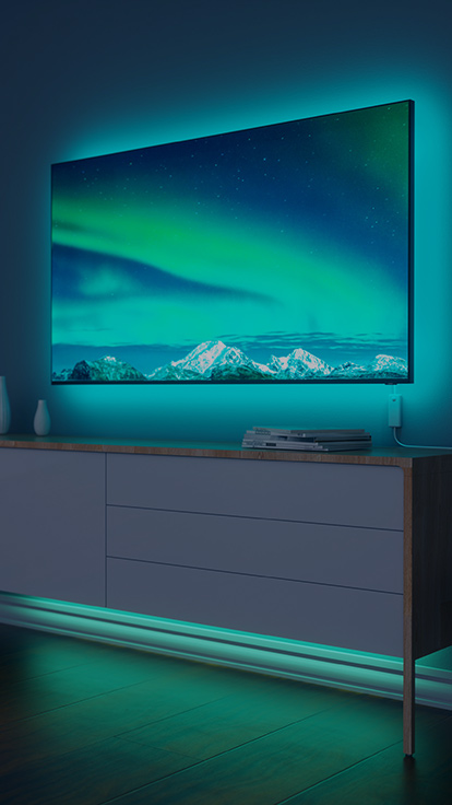Esta es una imagen de las tiras de luz led de Nanoleaf Essentials detrás de un televisor en una sala de estar. Las tiras de luz led que cambian de color brindan una agradable luz de fondo y brillo RGB.
