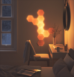 Esta es una imagen de un diseño de 10 paneles Nanoleaf Elements montados en la pared al lado de un escritorio en una habitación. Paneles de luz modulares inteligentes que se fijan a las paredes con los adhesivos incluidos y se conectan entre sí con conectores. Los Wood Look Hexagons son la pieza decorativa perfecta que agrega estilo y personalidad a la habitación, a la vez que funciona como una luz ambiental personalizable.