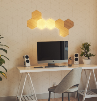 Esta es una imagen de un diseño de 7 paneles de Nanoleaf Elements Wood Look Hexagons montados en la pared por encima de una computadora. Estos paneles de luz inteligentes modulares crean un diseño único e iluminan tu espacio con un brillo natural. Las luces perfectas para iluminar tu oficina.
