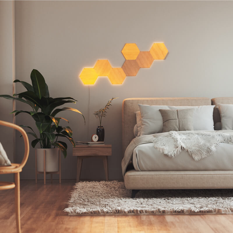 Nanoleaf Elements Thread-enabled wood-look hexagon smart modular light panels mounted to a wall in a bedroom. HomeKit, Google Assistant, Amazon Alexa, IFTTT.