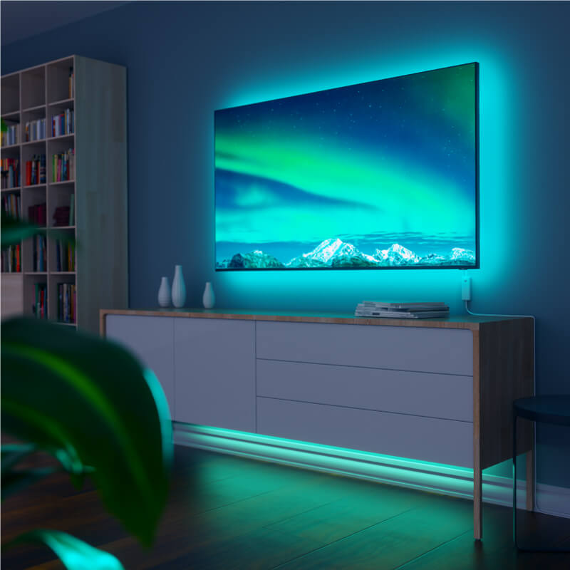 Tira de luz inteligente que cambia de color habilitada para Thread de Nanoleaf Essentials montada en un televisor en una sala de estar. Similar a Twinkly, Wyze. HomeKit, Google Assistant, Amazon Alexa, IFTTT.