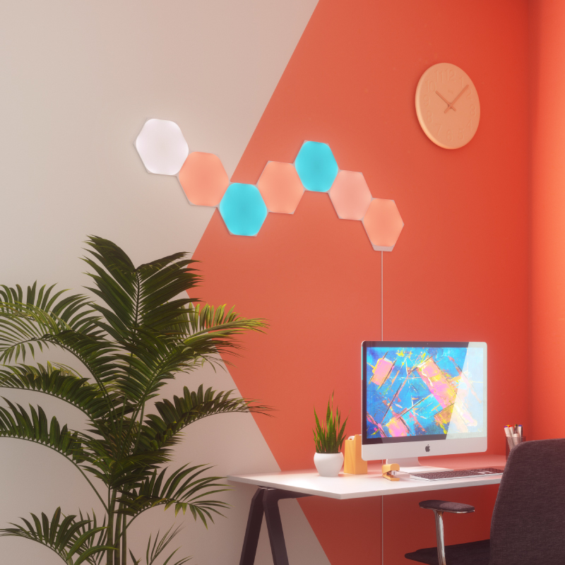 Nanoleaf Shapes Thread-enabled color-changing hexagon smart modular light panels mounted to a wall in a home office. Similar to Philips Hue, Lifx. HomeKit, Google Assistant, Amazon Alexa, IFTTT.